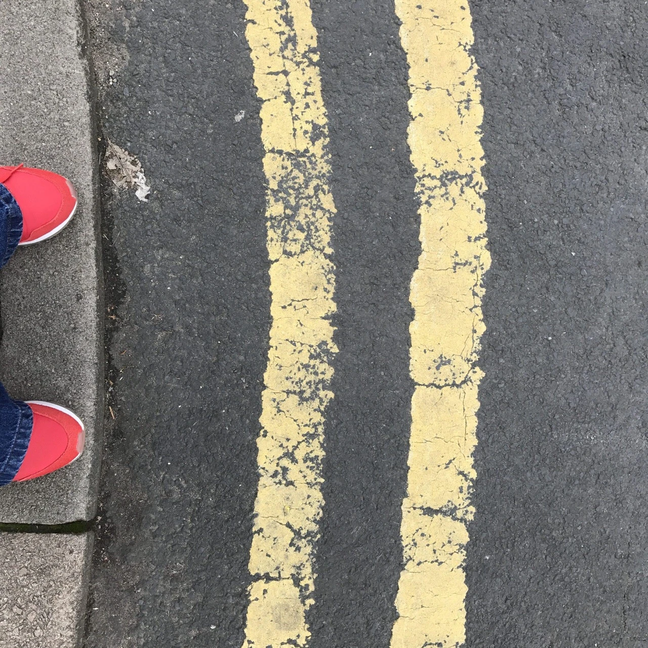 Red Shoes on Kerb next to Yellow Lines.